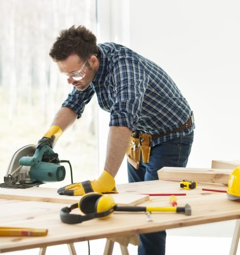 Carpenter cutting plank by circular saw
