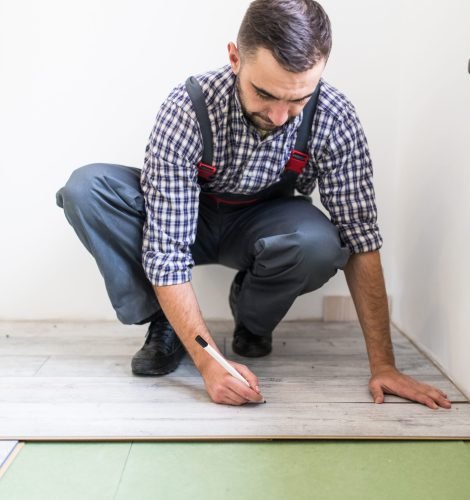 Young worker laying a floor with bright laminated flooring boards