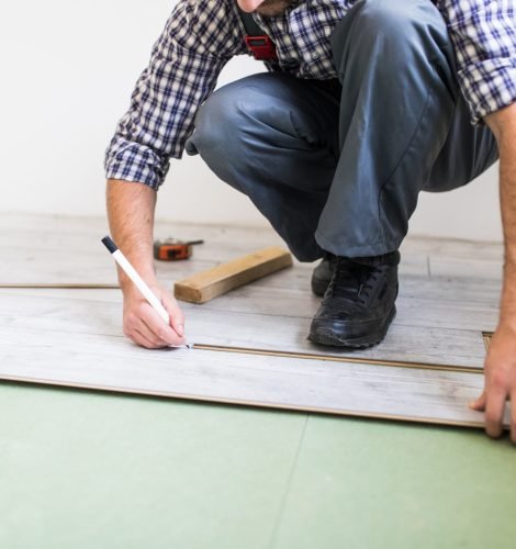 Young worker laying a floor with bright laminated flooring boards